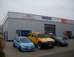 Electron Mobil Media Ladengeschäft mit einem hellblauen Nissan Micra, einem gelben Hummer H2 und einem Golf 5 Variant